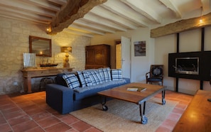 A cozy living room with a sofa, a coffee table, a TV, and a fireplace.