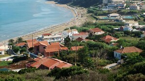A coastal residential area with houses, a beach, and a mountainous backdrop. - Terezas Hotel (Corfu)