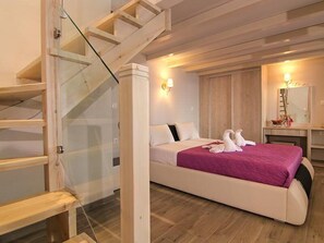 A bedroom with a large bed, a wooden staircase, and a mirror above the bed. - Terezas Hotel (Corfu)