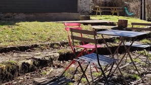 A house with a dark garage door, a red bench, and a picnic table in the yard. - Between Sainte Marie de Campan and La Mongie. (Campan)