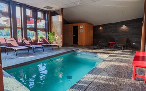 An indoor swimming pool with lounge chairs and a small table, surrounded by large windows. - When heritage, art and well-being meet (CANDES SAINT MARTIN)