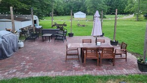 A patio area with a brick floor, wooden tables and chairs, and string lights. - Sunset cottage complete w/large deck, fire pit and mins away from public beach (Lake Milton)