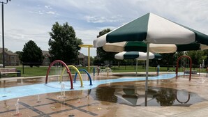 A water play area with multiple water jets and a covered seating area. - Charming Colonial Home with Private Chipping Green (Hutchinson)