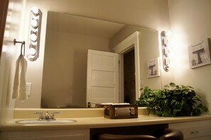 A bathroom with a sink, mirror, and lights. - Charming Colonial Home with Private Chipping Green (Hutchinson)