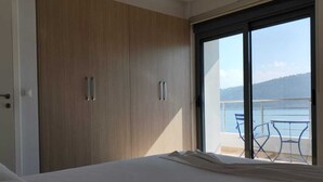 A bedroom with a bed, wooden wardrobe, and a balcony with a table and chairs.