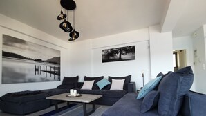 A modern living room with a sectional sofa, a coffee table, and a large painting of a landscape.
