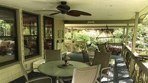 A covered patio with a table and chairs, a ceiling fan, and a view of the garden.