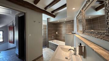 Un baño moderno con un espejo grande, una bañera y un lavamanos.
