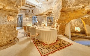 A dining area with stone walls, a chandelier, and a table set for four. - When heritage, art and well-being meet (Candes-Saint-Martin)