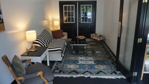 A cozy living room with a black and white striped sofa, a small table with a lamp, and a patterned rug. - The Mighty Fraser Motel (Boston Bar)