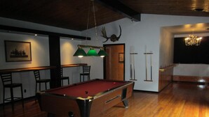 A billiards room with a pool table, wooden chairs, a chandelier, and a framed picture on the wall. - The Mighty Fraser Motel (Boston Bar)