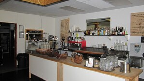 A bar area with a wooden counter, various bottles, glasses, and a menu board. - The Mighty Fraser Motel (Boston Bar)