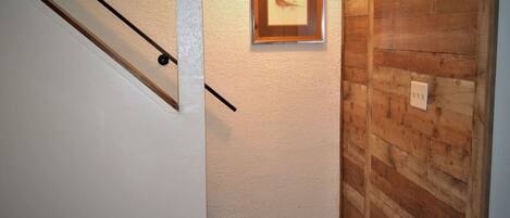 A hallway with a wooden wall, a framed picture, and a staircase.