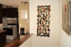 A kitchen with a modern stove, a coffee maker, and a wall art piece. - Urbana – Charming, Bright 2-Bedroom, 1.5-Bath Apartment in the Heart of Grand Forks (Grand Forks)
