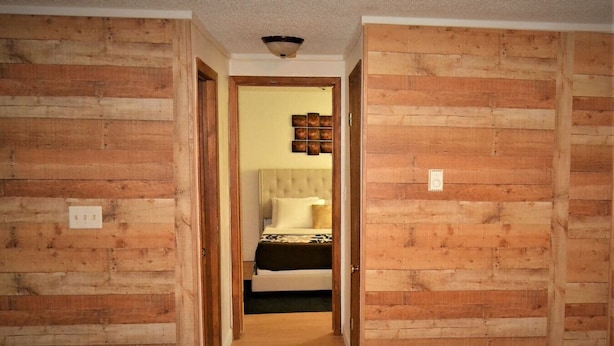 Ein schmaler Korridor mit holzverkleideten Wänden und einem Bett im Hintergrund.
