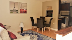 Ein kompakter Wohnbereich mit Essplatz, einer Couch, einer Lampe und einer Küchenzeile.