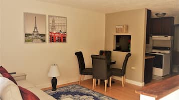 Un espace de vie compact comprenant un coin repas, un canapé, une lampe et un coin cuisine.