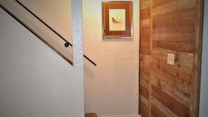 Ein Flur mit Holzwand, einem gerahmten Bild und einer Treppe.