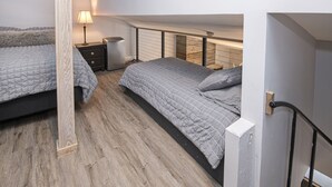 A bedroom with two beds, a nightstand, a lamp, and a wooden floor. - Unit 14 WITH AC-NEW LOWER PRICE. HEART OF VAIL. WALK TO GONDOLA (Vail)