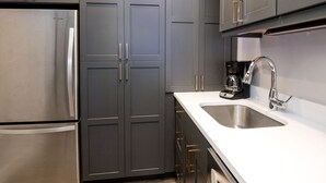 A modern kitchen with dark grey cabinets, stainless steel appliances, and a white countertop. - Unit 14 WITH AC-NEW LOWER PRICE. HEART OF VAIL. WALK TO GONDOLA (Vail)