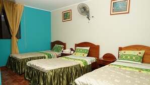 A hotel room with two single beds, a wooden headboard, a fan, and a window with curtains. - Hospedaje Orbis (Pichanaqui)