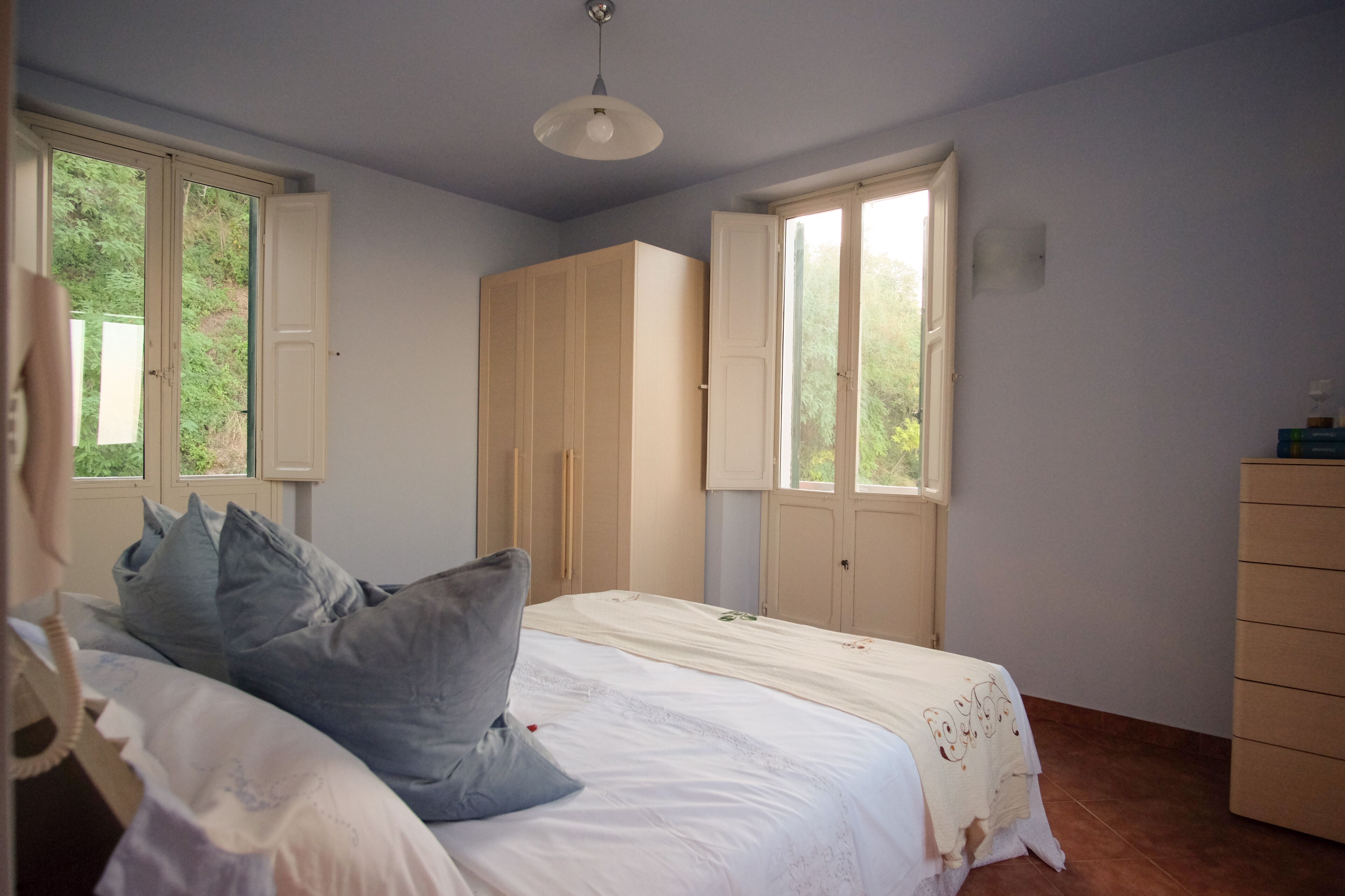 Une chambre à coucher avec un lit, deux fenêtres, une armoire et une commode.