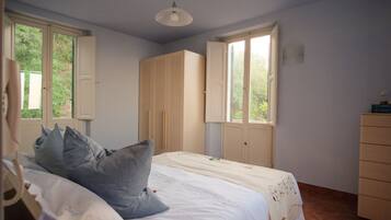 Une chambre à coucher avec un lit, deux fenêtres, une armoire et une commode.