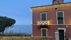 Un bâtiment rouge avec un balcon, des volets verts et une horloge.