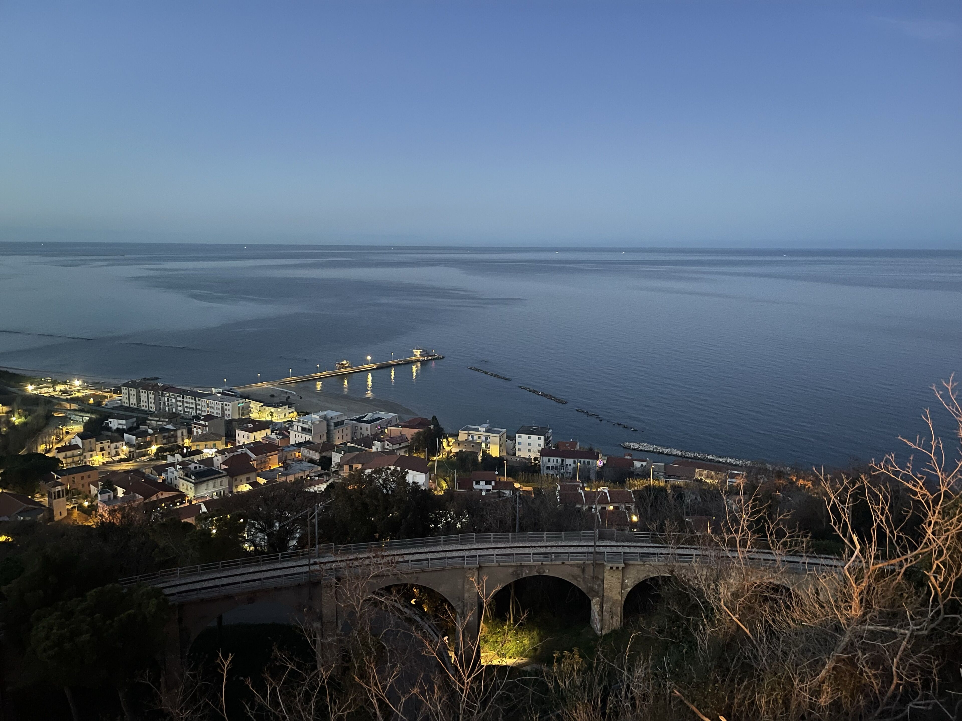 Un pueblo costero con un puente destacado y un muelle que se adentra en el mar.