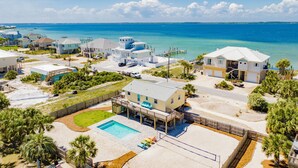 Un área residencial costera con casas, una piscina y un muelle que se adentra en el agua.