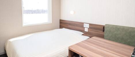 Une chambre d’hôtel avec un lit, un bureau, une chaise, une fenêtre et une vue sur l’extérieur.