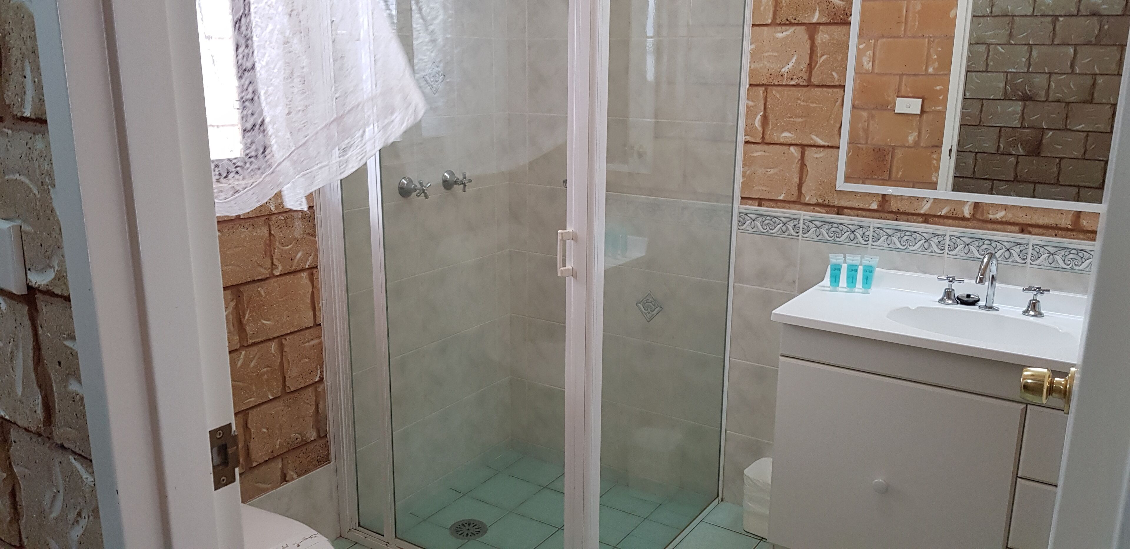 Une salle de bain avec une douche à parois de verre, un lavabo blanc et un miroir au-dessus.