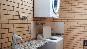 Une petite salle de bain équipée d’un lave-linge, de toilettes et d’un lavabo.
