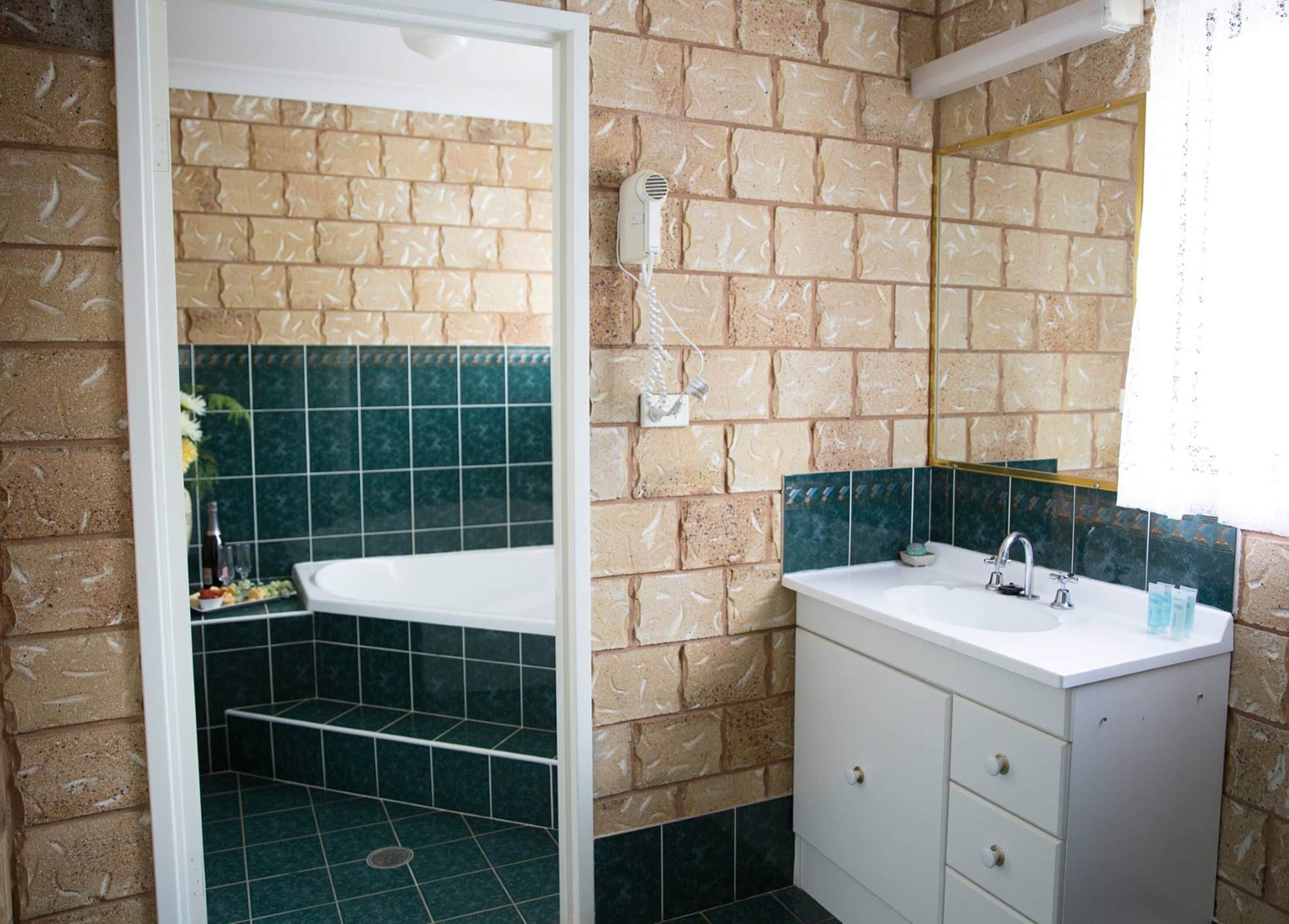 Un baño con ducha, lavamanos y espejo.