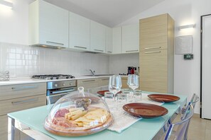 Une cuisine moderne avec des meubles blancs, une cuisinière et un coin repas avec une table mise pour deux personnes.