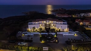 A hotel with a central courtyard, a pool, and a view of the sea at night. - Unique Holiday Apartment "Villa Marconi 8" with Sea View & Spacious Sun Terrace (Golfo Aranci)