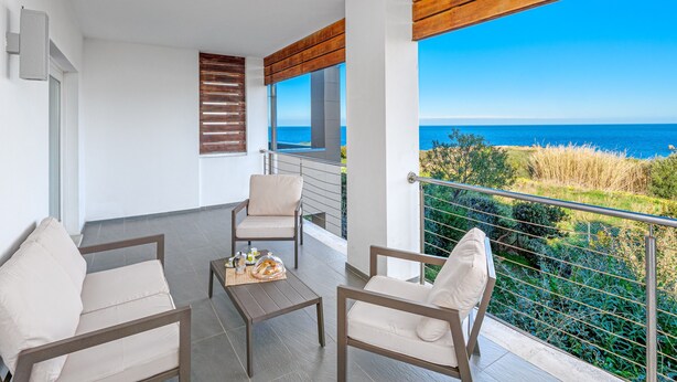 A balcony with two chairs, a small table, and a view of the sea. - Unique Holiday Apartment "Villa Marconi 8" with Sea View & Spacious Sun Terrace (Golfo Aranci)