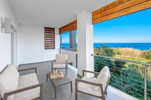 Ein Balkon mit zwei Stühlen, einem kleinen Tisch und Meerblick.