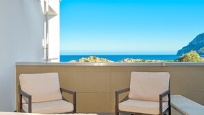Ein Balkon mit zwei Stühlen und Blick auf das Meer und eine Klippe.