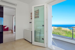 Une pièce dotée d’une porte-fenêtre coulissante donnant sur un balcon avec vue sur la mer.