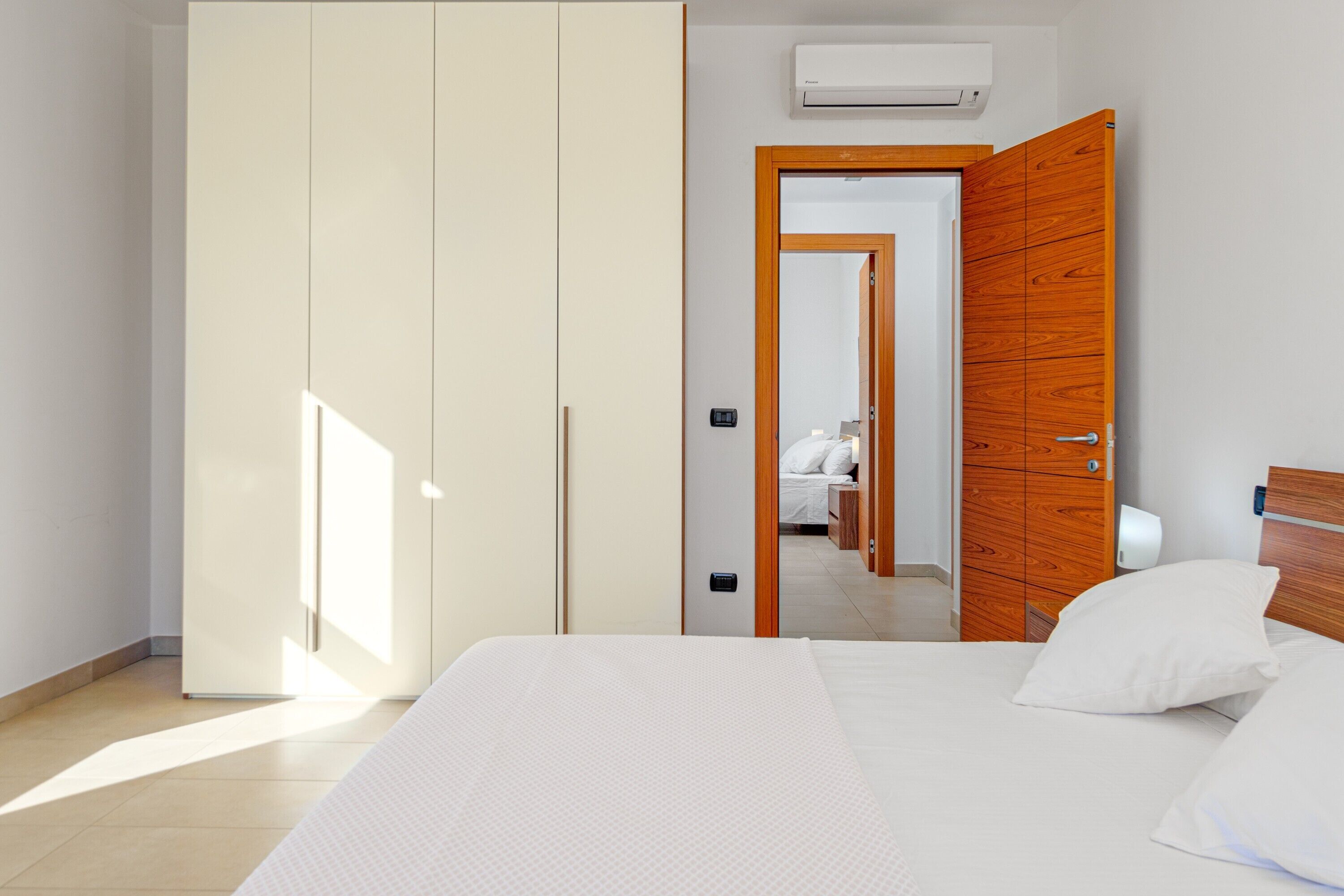 A bedroom with a bed, a wardrobe, and a bathroom visible through an open door.