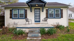 A two-story house with a front porch, two windows with shutters, and a blue door.