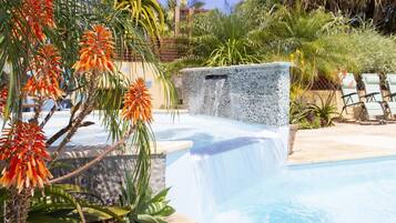 Alberca al aire libre, sombrillas en la alberca y camastros