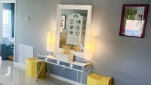 A room with a vanity table, a mirror, two lamps, and a framed picture on the wall. - Lux Long Term Condominium (South Padre Island)