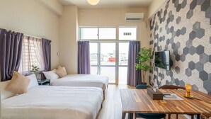 Een hotelkamer met twee bedden, een houten eettafel, een aan de muur bevestigde televisie en een groot raam met gordijnen.