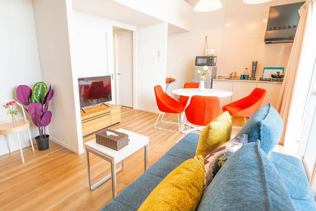 Een moderne woonkamer met een bank, een salontafel en een eethoek met rode stoelen.