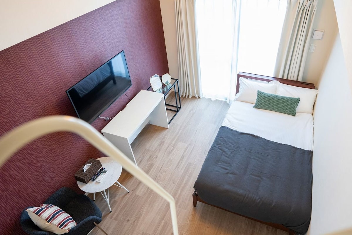 Een hotelkamer met een bed, televisie, bureau en stoel.