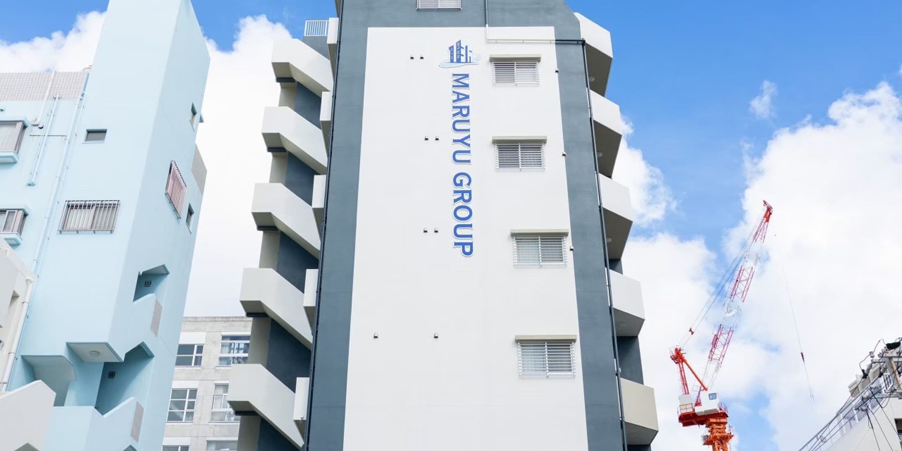 A modern building with the name "MARUYU GROUP" prominently displayed on its facade.