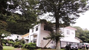 A two-story building with a white exterior, a visible staircase, and parked cars in front. - Shintaku Sanso (Minamimaki)