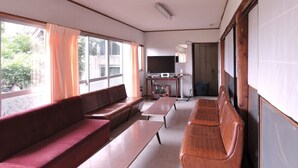 A spacious living area with a large window, a sofa, a television, and a small table. - Shintaku Sanso (Minamimaki)